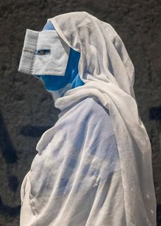 a person wearing a white and blue outfit with a face covering on their head,