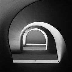 a black and white photo of an arch with a bench in the center, taken from below