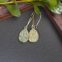 Pretty botanical charms in a teardrop shape. The gold plated charms have a subtle blue green patina to highlight the design. The charms hang from gold plated kidney shaped ear wires.  Earring Length: 1 3/4" including wire Charm Size: about 3/4" high by 1/2" wide  Your earrings will arrive in a eco-friendly Kraft paper gift box. You May Also Like: https://www.etsy.com/shop/BonArtsStudio?ref=hdr_shop_menu&search_query=patina+earrings Flower Earring Collection: https://www.etsy.com/shop/BonArtsStudio?ref=hdr_shop_menu&search_query=flower+earring See What's New: https://www.etsy.com/shop/BonArtsStudio?ref=hdr_shop_menu&section_id=23290134 My Shop Link: https://www.etsy.com/shop/BonArtsStudio Close-up photos showing item details may make an item appear larger - please check measurements and des Brass Long Drop Teardrop Earrings As Gift, Gift Teardrop Earrings With Lever Back Ear Wires, Gift Teardrop Earrings With Lever Back, Long Drop Brass Teardrop Earrings For Gift, Handmade Gold Teardrop Earrings, Handmade Gold Teardrop Pendant Earrings, Gift Brass Teardrop Drop Earrings, Gold Teardrop Jewelry With Flower Charm, Handmade Gold Teardrop Long Drop Earrings