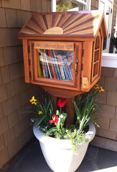 a potted planter filled with flowers and books on the side of a house