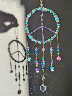 a peace sign hanging from the side of a wall with beads and jewels on it