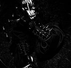 a person wearing a mask and holding a knife in their hand, sitting on the ground