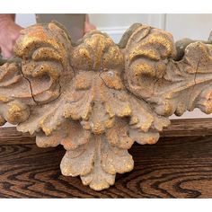 a close up of a decorative object on a wooden surface with a person holding it in the background