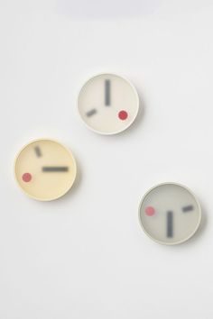 three plates with faces painted on them sitting next to each other in the shape of clocks