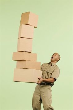 a man is carrying several boxes on his back while standing in front of a green background