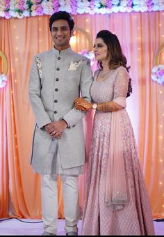 a man and woman standing next to each other in front of a floral decorated stage