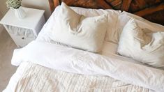 a bed with white linens and striped pillows