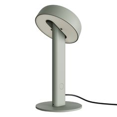 a white table lamp sitting on top of a metal stand with a cord plugged into it