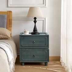 This nightstand brings a touch of farmhouse charm and transitional style to your bedroom. Crafted from kiln-dried solid paulownia wood, it features a stacked, rectangular shape with a finished back, ensuring it looks great from every angle. The two drawers glide smoothly on roller glides, offering easy access to your bedside essentials. Antique bronze ring handles add a vintage touch, complementing the rustic appeal of the paneled drawer fronts. With its versatile design, this nightstand can als Blue Nightstand, Antique Bedside Tables, Transitional Nightstand, Bronze Handles, Bedside Essentials, Rustic Nightstand, Paulownia Wood, Primary Bedroom, Nursery Furniture Sets