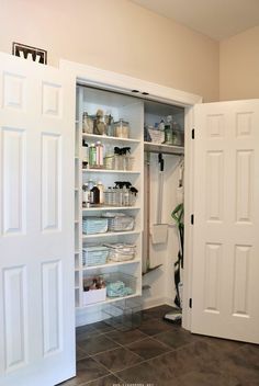 an open pantry with doors and shelves full of items in the closet, next to a tiled floor