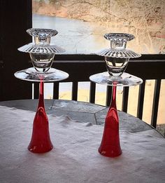 two red glass candlesticks sitting on top of a table next to each other