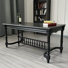 a table with books and a book case in the background on a hard wood floor