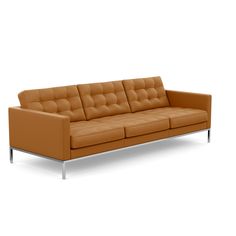 a tan leather couch with chrome legs on an isolated white background in front of a plain backdrop