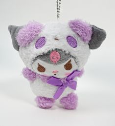 a small stuffed animal with a purple bow on it's neck and ears is hanging from a keychain