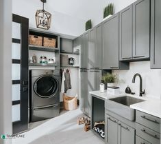 a washer and dryer in a room with gray cabinets, white counter tops