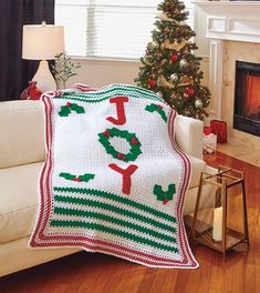 a living room with a christmas tree and a white couch covered in a crocheted blanket