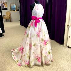 a dress on display in front of purple curtained room with mannequins