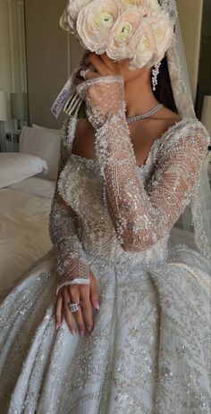 a woman in a wedding dress with flowers on her head and hands to her face