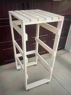 a white wooden shelf sitting on top of a floor next to a garage door with brown shutters