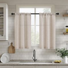 a kitchen with white cabinets and countertops has a window in the middle that is open to let natural light into the room