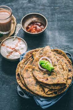 some food is sitting on a table next to cups and sauces