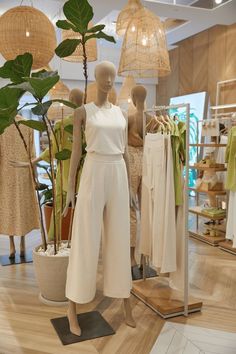 mannequins are displayed in a clothing store with wooden flooring and hanging lights