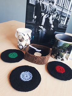 four crocheted coasters sitting on top of a table next to a coffee cup