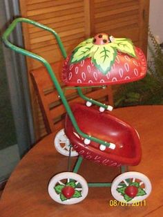 a red toy stroller sitting on top of a wooden table