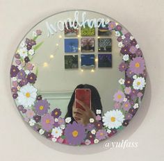 a woman taking a selfie in front of a mirror with flowers on the frame