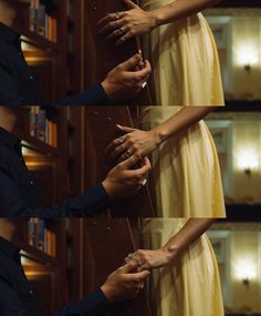 the hands of two people are touching each other's fingers in front of bookshelves