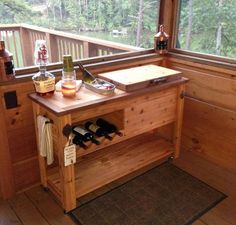 a wooden table with bottles and wine glasses on it in front of a large window