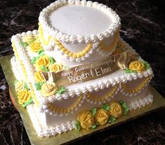 a three tiered cake with yellow roses on the bottom and white frosting in the middle