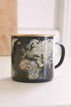 a black and gold colored coffee mug with a map on the inside, sitting on a white counter