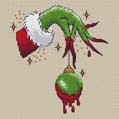 a cross stitch christmas ornament with an elf's hat hanging from it