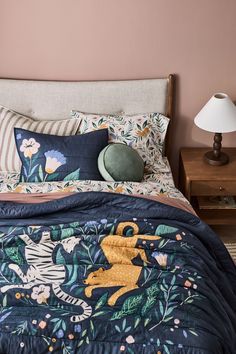 a bed with a blue comforter and pillows on top of it next to a night stand