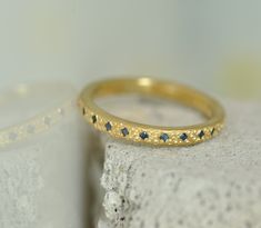 a close up of a gold ring with blue stones on the surface next to it