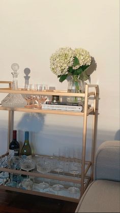 a gold bar cart with wine glasses and bottles on it