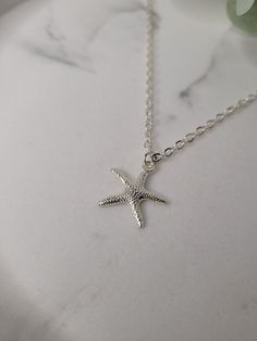 Silver plated starfish charm attached to an 18inch silver plated sparkle chain necklace with lobster claw closure. The charm is attached to the necklace via a silver plated jump ring. The charm measures 1.9cm long x 1.9cm wide. The necklace measures 18inches. This super cute starfish necklace is a great reminder of times spent near the seaside. The necklace will come gift wrapped in tissue paper and an organza bag. Please note that although I have endeavour to show of my pieces in the best, natural light, the colour may vary slightly due to screen resolution/brightness. However, if you have any questions then please feel free to message me. Ocean-inspired Pendant Necklace With Lobster Clasp, Adjustable Silver Charm Necklaces With Star Charm, Adjustable Starfish Charm Jewelry, Adjustable Star-shaped Jewelry With Starfish Charm, Silver Star-shaped Adjustable Necklace, Adjustable Sterling Silver Charm Necklaces With Star Charm, Adjustable Sterling Silver Star Charm Necklace, Adjustable Star-shaped Sterling Silver Necklaces, Dainty Starfish Necklace For Beach