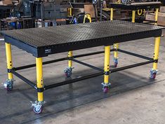 two black tables with yellow wheels in a warehouse