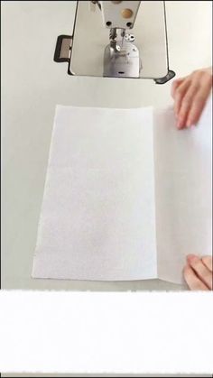 someone is holding up a piece of paper to make a photo album on the table