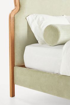 an upholstered bed with white sheets and pillows