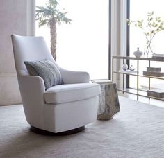 a white chair sitting on top of a rug in a living room next to a window