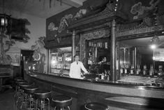 an old photo of a man behind the bar