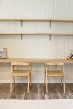 two wooden chairs sitting on top of a hard wood floor next to a book shelf