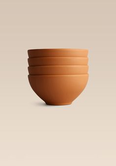 three brown bowls stacked on top of each other in front of a beige background,