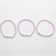 This exquisite Neshama bracelet set features three delicate bracelets crafted with lavender glass beads. Each bracelet bears the word "נשמה" in Hebrew letters, "Neshama" in English, and "Soul" in English. These elegant and meaningful bracelets blend traditional design with a contemporary touch, embodying the essence of spirituality and style. Lavender Bracelets With Tiny Beads For Gift, Lavender Beaded Bracelet With Tiny Beads For Gifts, Purple Stretch Bracelet With Tiny Beads As Gift, Handmade Purple Name Bracelet With Round Beads, Lavender Bracelets With Spacer Beads As Gift, Lavender Bracelets With Spacer Beads For Gift, Adjustable Lavender Beaded Bracelets With Letter Beads, Lavender Beaded Bracelets With Round Beads As Gift, Personalized Purple Beaded Bracelet