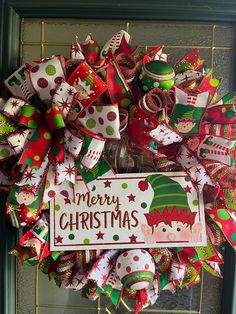 a christmas wreath on the front door with decorations around it and a merry sign in the center