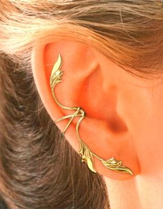 a woman's ear with gold leaves on it