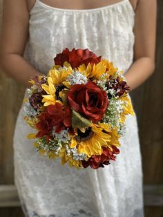 a bridal holding a bouquet of sunflowers and red roses in her hands