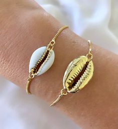 Features genuine Cowrie Shells, dipped in gold plating and affixed to a 14k gold filled box style chain. The bracelet is fully adjustable for a customized fit. Simply slide the gripper disc to your liking. It holds securely. Choose from White with gold trim or All gold. (Bamboo Cuff bracelet shown layered is available separately in the shop) Makes a great gift! I have Cowrie Necklaces available in the shop as well, so take a look around! *Please avoid showering, swimming or spraying perfume with Adjustable Gold Plated Jewelry For Gift, Adjustable Gold-plated Jewelry For Gifts, Trendy Resizable Gold Jewelry, White Resizable Bracelet, White Resizable Bracelet Jewelry, Adjustable Nickel-free Yellow Gold Jewelry, Adjustable Tarnish Resistant Jewelry Gift, Dainty White Resizable Jewelry, Trendy Gold Jewelry With Adjustable Length